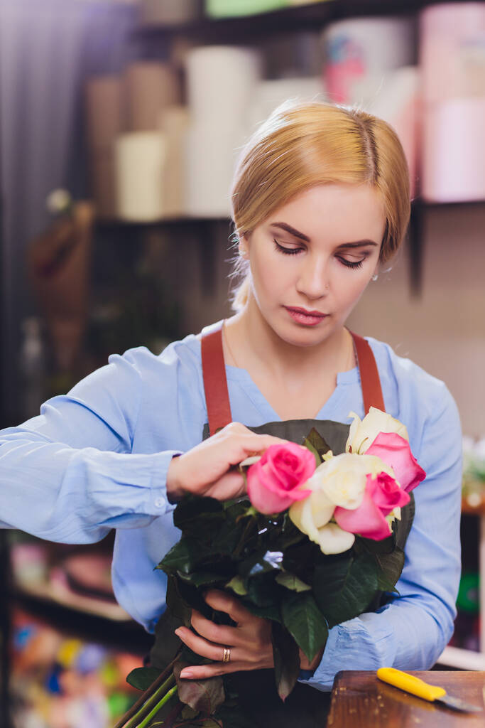 Asystentka sprzedaży kobiet pracuje jako kwiaciarnia i trzymając bukiet z klientem w tle. Poziomy kształt, talia w górę. - Zdjęcie, obraz