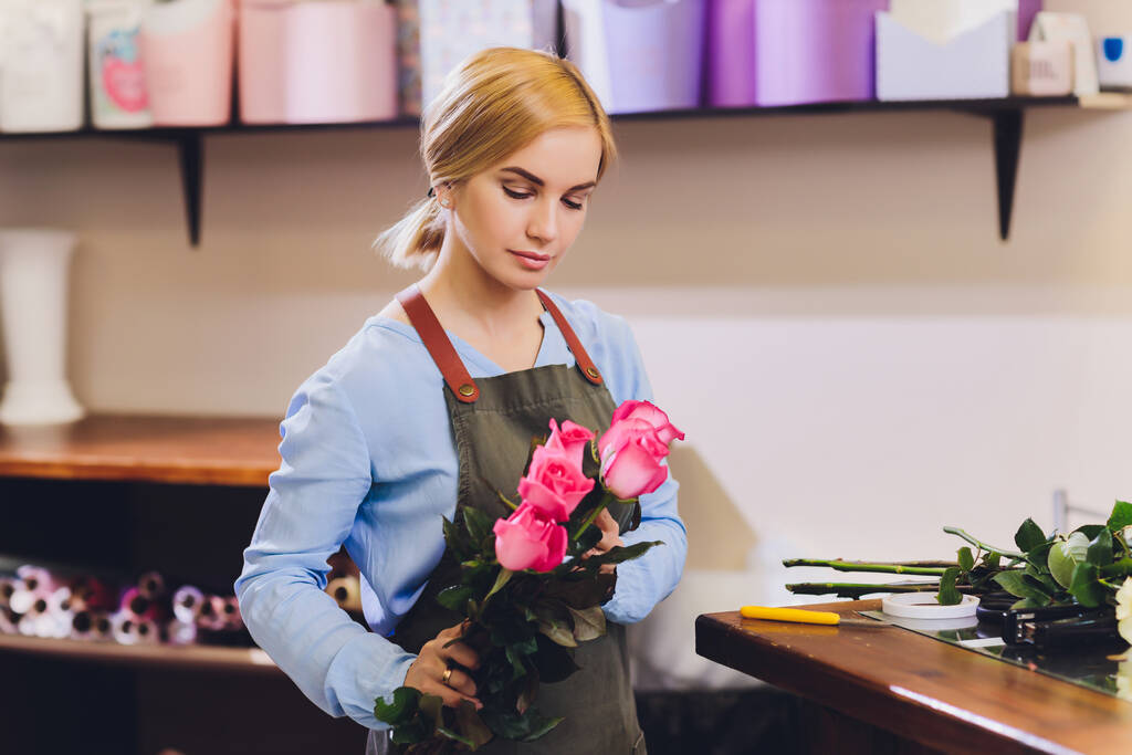 花屋として働いている女性セールスアシスタントと背景に顧客と花束を保持します。水平形状、腰まで. - 写真・画像