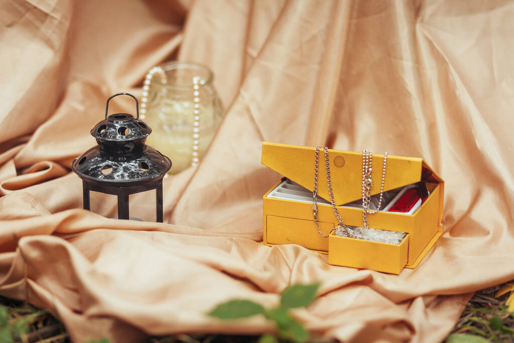 Una caja con una cadena de oro y un candelero está sobre un mantel de seda
 - Foto, Imagen