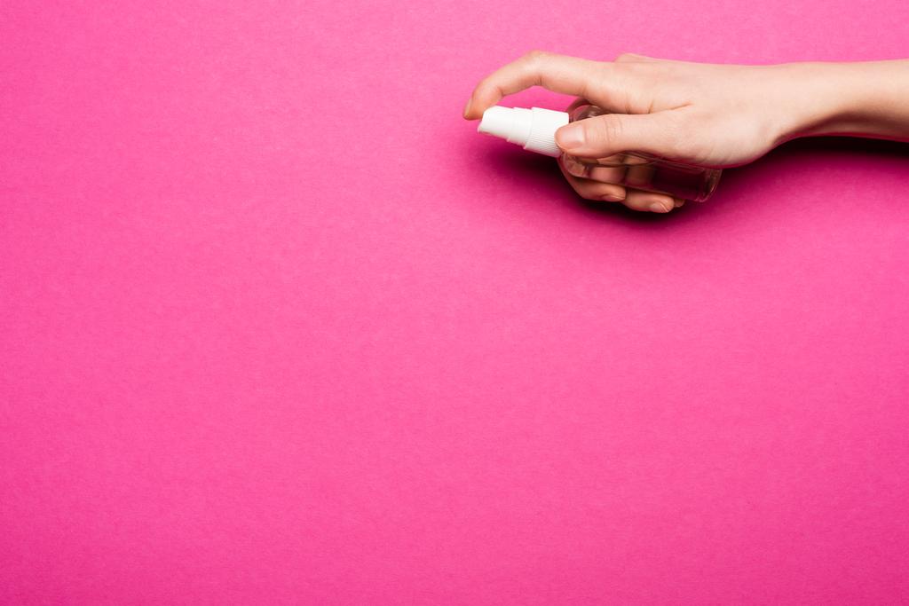 vue recadrée de femme pulvérisation désinfectant pour les mains sur rose - Photo, image