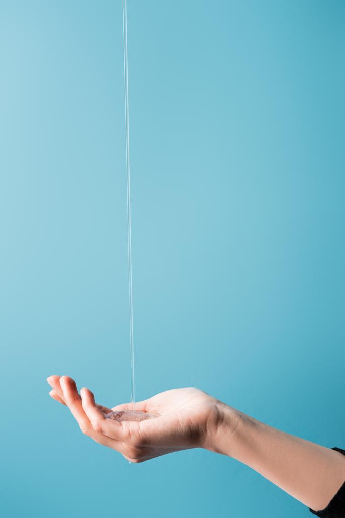 vista recortada de la mano femenina bajo jabón líquido fluido en azul
 - Foto, Imagen