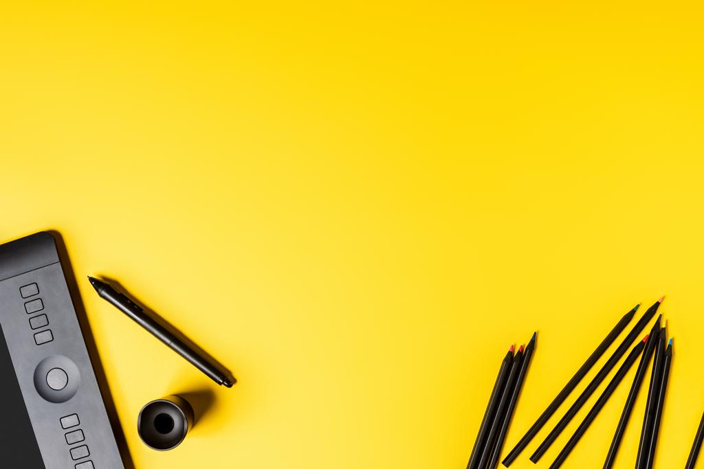 vista dall'alto del disegno tavoletta e matite vicino stilo su giallo
 - Foto, immagini