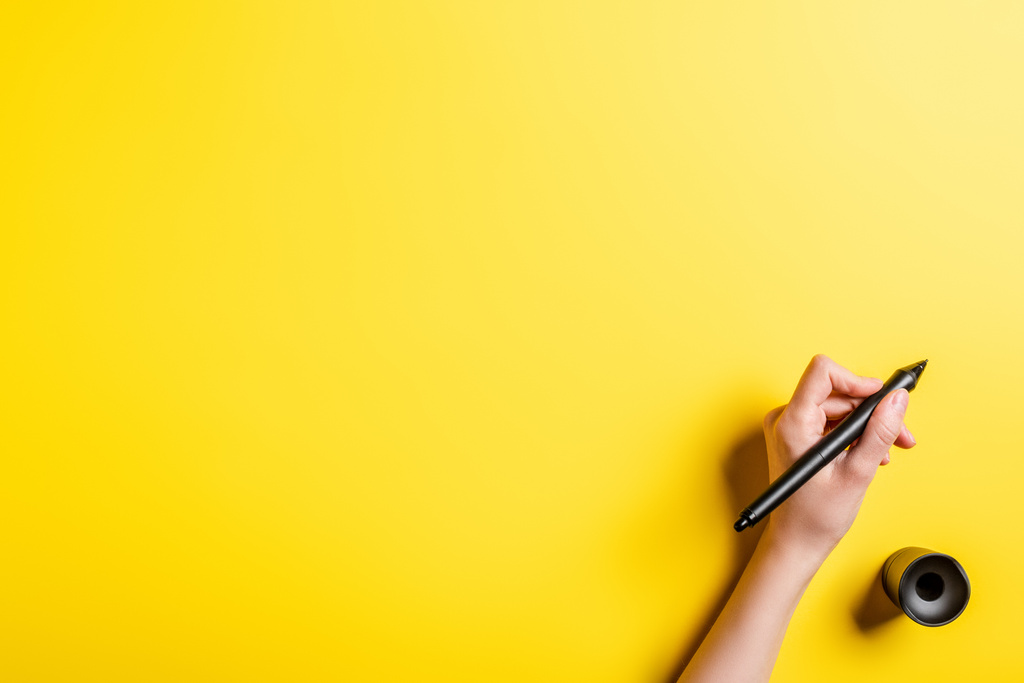 vista recortada del diseñador sosteniendo lápiz cerca del soporte de lápiz en amarillo
  - Foto, Imagen