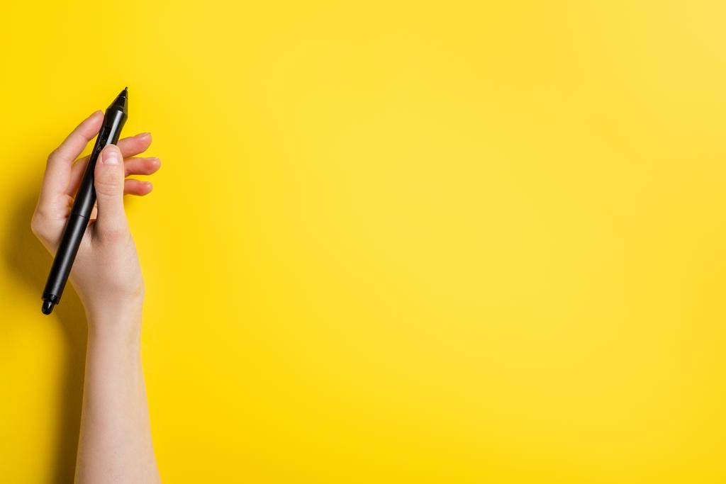 cropped view of designer holding black stylus on yellow  - Photo, Image