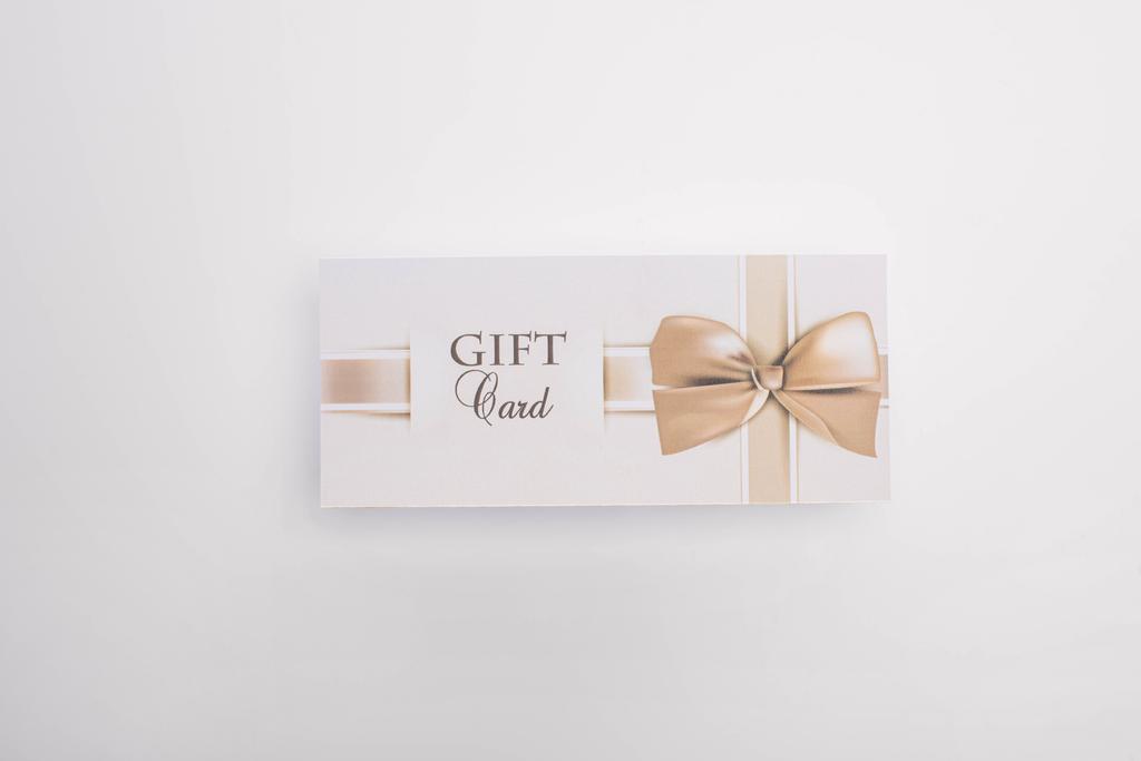 Bovenaanzicht van cadeaukaart met strik op witte achtergrond - Foto, afbeelding