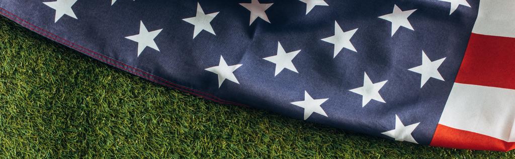 οριζόντια καλλιέργεια της αμερικανικής σημαίας με αστέρια και ρίγες στο πράσινο γρασίδι έξω, έννοια ημέρα εργασίας  - Φωτογραφία, εικόνα