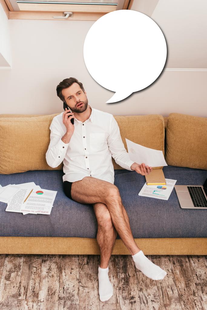 Freelancer bonito em camisa e calcinha falando no smartphone e segurando documento no sofá, ilustração bolha discurso em branco
 - Foto, Imagem