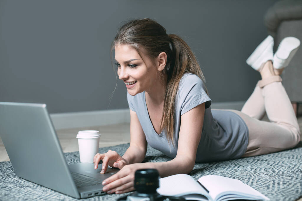 Mujer joven usando el ordenador portátil, se comunica en Internet con el cliente. Acogedor lugar de trabajo de oficina en casa
. - Foto, Imagen