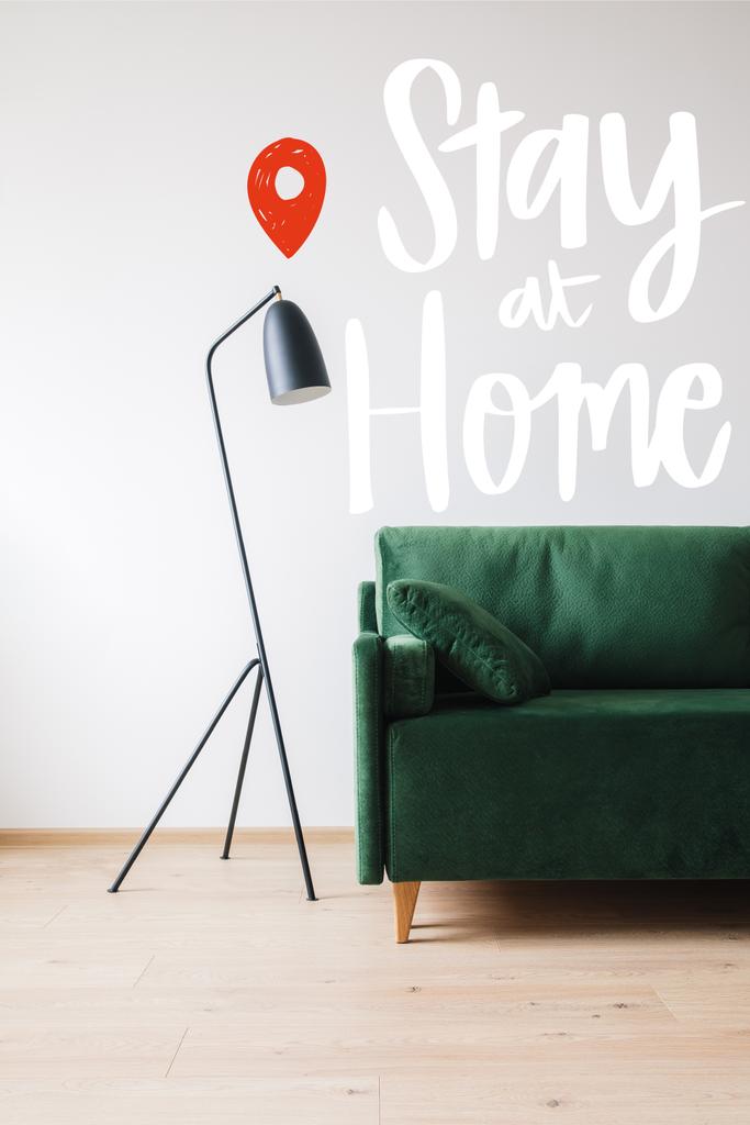 green sofa with pillow near modern floor lamp and stay at home lettering - Photo, Image