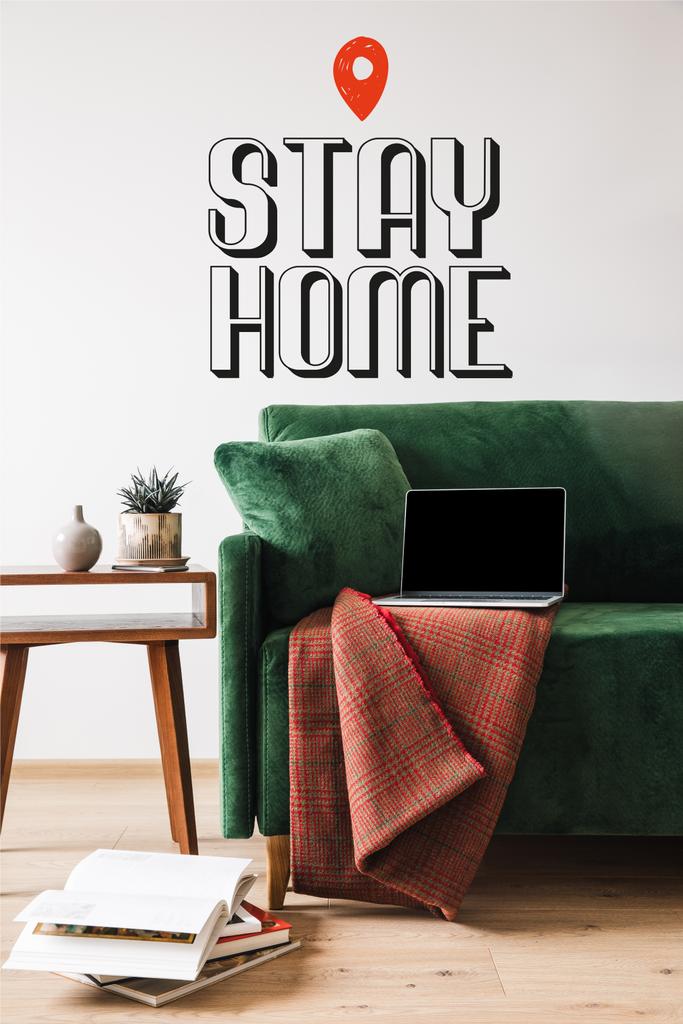 зеленый диван с одеялом и ноутбуком рядом с деревянным журнальным столиком и остаться дома буквы
 - Фото, изображение