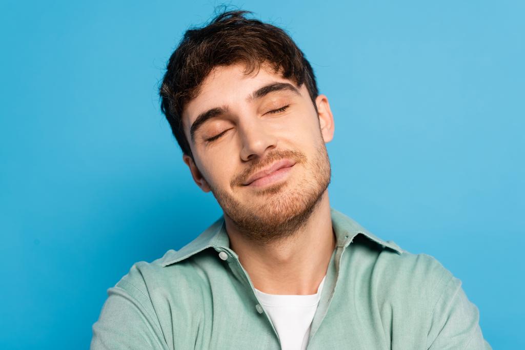 радостный молодой человек, мечтающий с закрытыми глазами на голубом
 - Фото, изображение