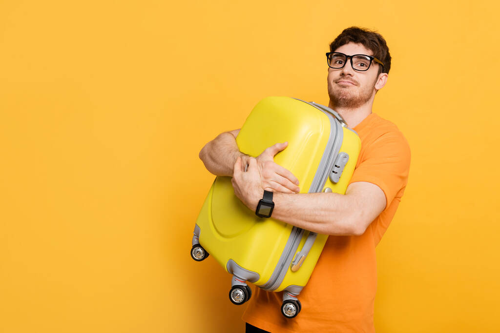 divertido turista masculino celebración maleta para vacaciones de verano en amarillo
  - Foto, imagen