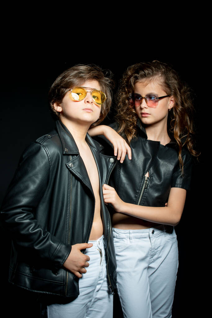 préadolescent garçon et fille en cuir vêtements posant en studio sur fond sombre - Photo, image