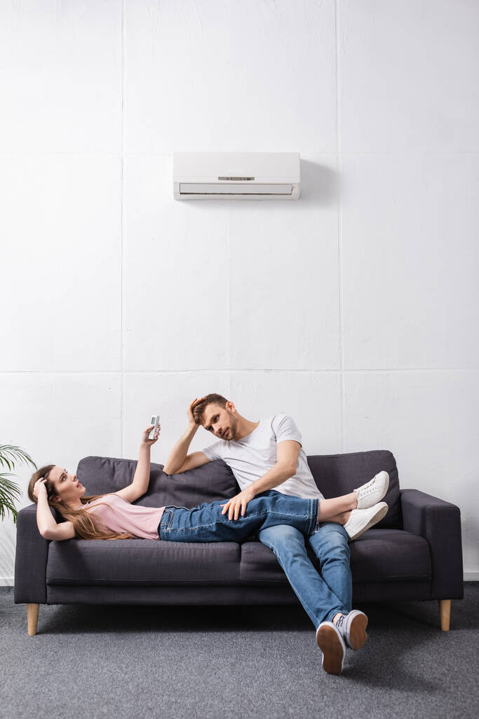 zaměnitelný pár s dálkovým ovladačem trpícím teplem doma s rozbitou klimatizací  - Fotografie, Obrázek
