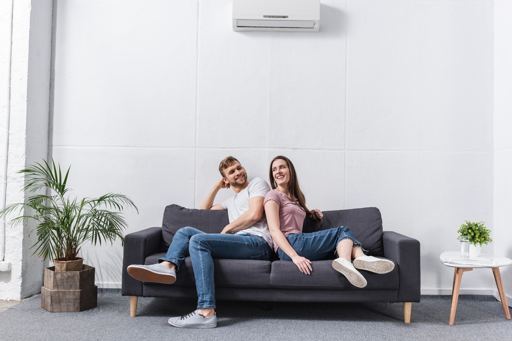positive girlfriend and boyfriend hugging at home with air conditioner - Photo, Image