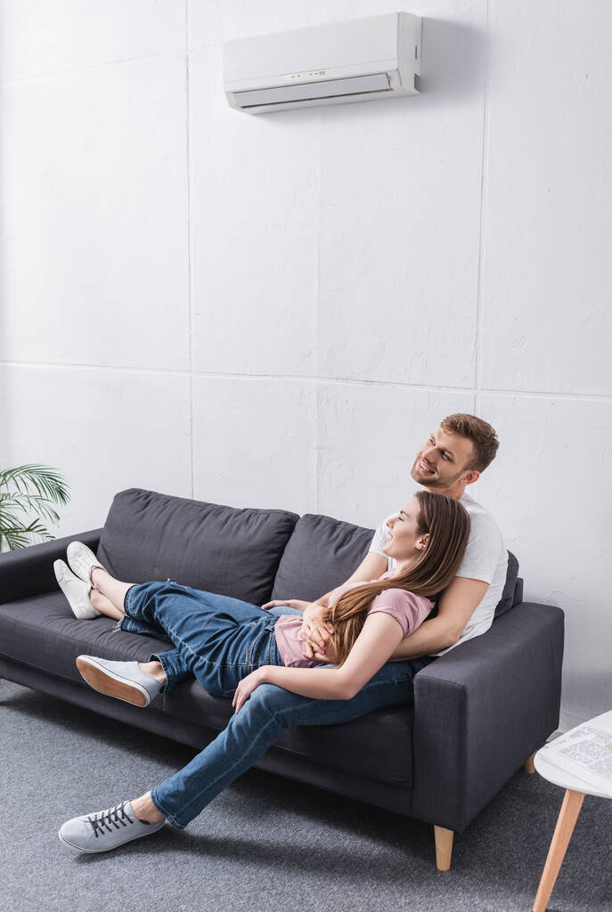 joven feliz pareja abrazándose en casa con aire acondicionado
 - Foto, Imagen
