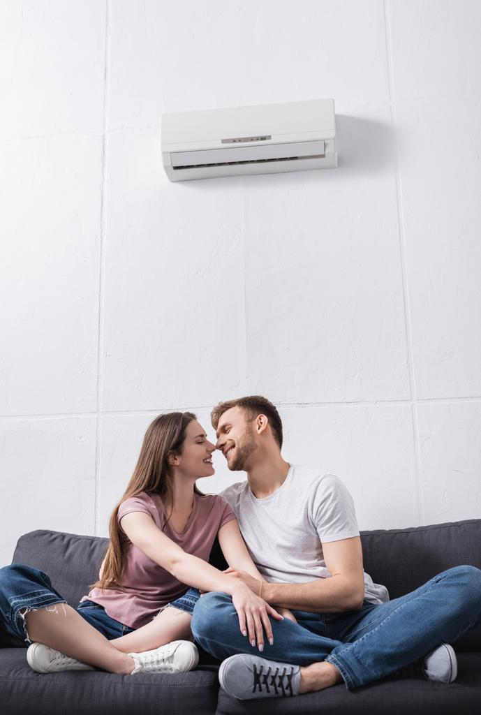 positiivinen tyttöystävä ja poikaystävä halaus ja menossa suudella kotona ilmastointilaite - Valokuva, kuva
