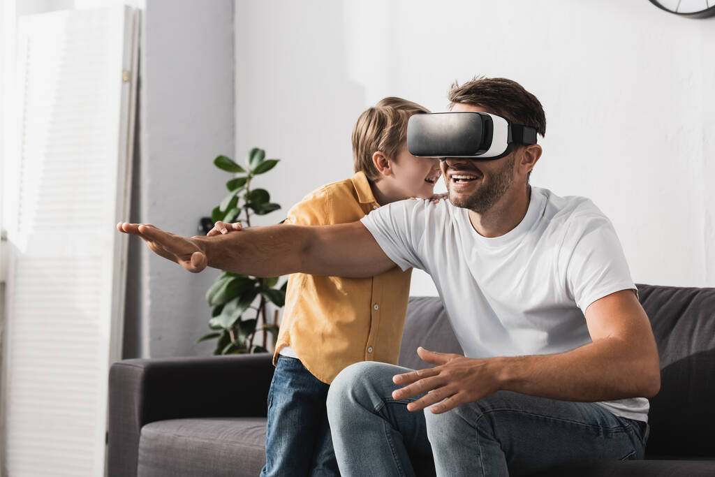 smiling man in vr headset sitting with outstretched hand near adorable son  - Photo, Image