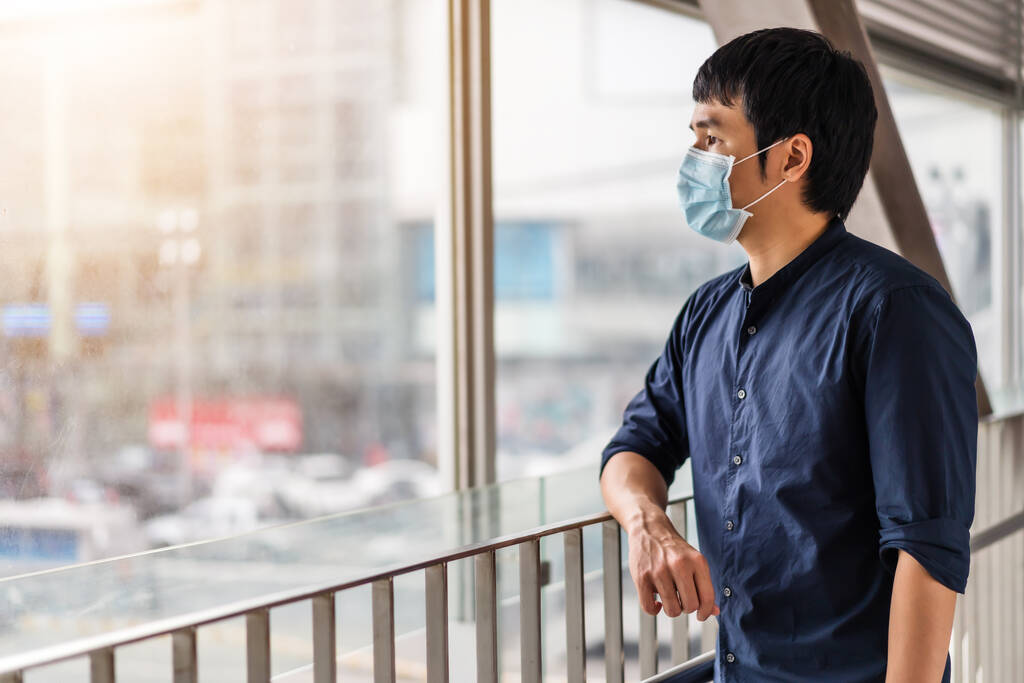 nuori aasialainen mies yllään lääketieteellinen naamio ehkäisyyn koronavirus (Covid-19) pandemia kaupungissa. uudet normaalit käsitteet - Valokuva, kuva
