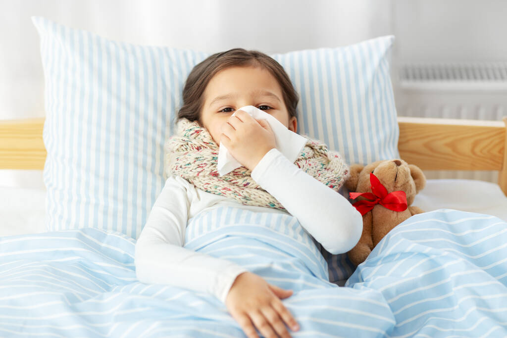 άρρωστο κορίτσι ξαπλωμένο στο κρεβάτι και φυσώντας μύτη στο σπίτι - Φωτογραφία, εικόνα