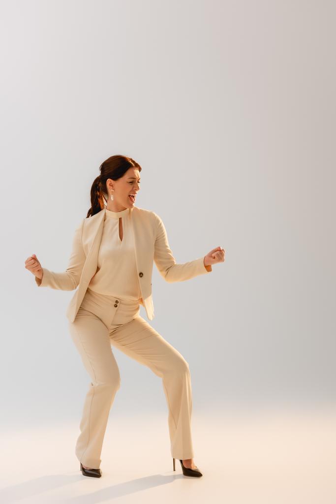 Positive Geschäftsfrau zeigt yeah Geste auf grauem Hintergrund, Konzept des Körpers positiv  - Foto, Bild