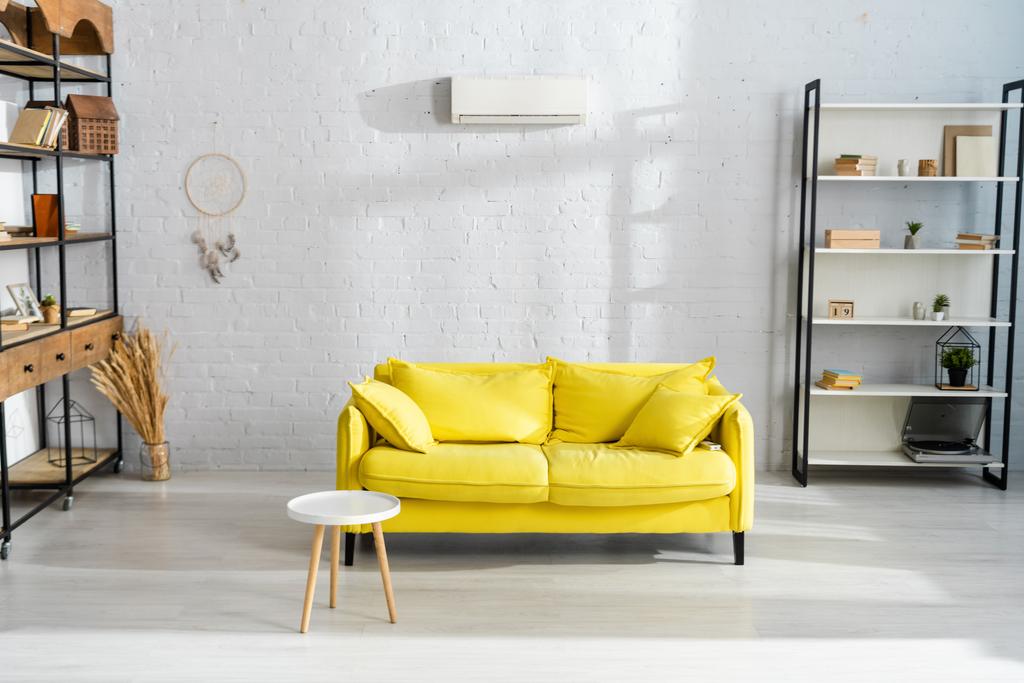 Interieur des Wohnzimmers mit Couchtisch in der Nähe der gelben Couch  - Foto, Bild