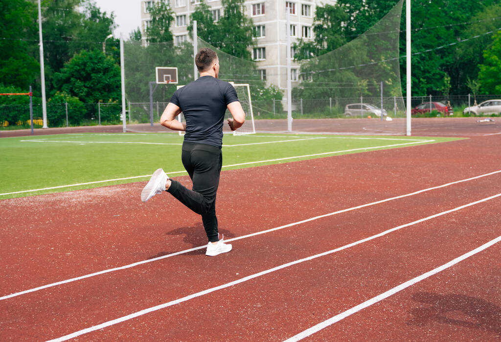 Чоловік-спортсмен біжить на спортивній червоній біговій доріжці. Концепція здорового способу життя
 - Фото, зображення