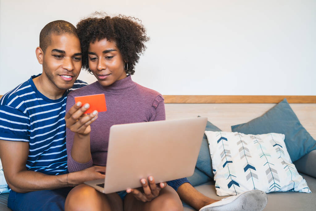 Porträt eines glücklichen jungen Paares beim Online-Shopping mit Kreditkarte und Laptop zu Hause. Online einkaufen und Beziehungskonzept. - Foto, Bild