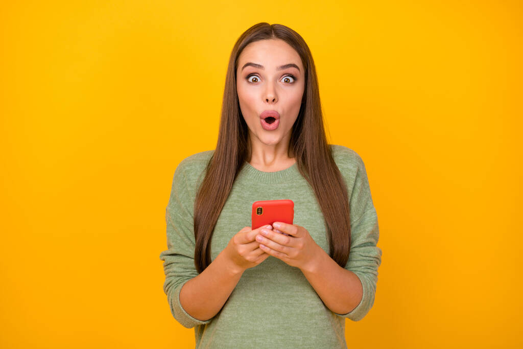 Πορτρέτο του έκπληκτου κοριτσιού χρήση έξυπνο τηλέφωνο εντυπωσιασμένη επικοινωνία κοινωνικό δίκτυο κουβέντα φίλος απάντηση κραυγή wow omg φορούν πουλόβερ απομονώνονται πάνω λάμψη φόντο χρώμα - Φωτογραφία, εικόνα