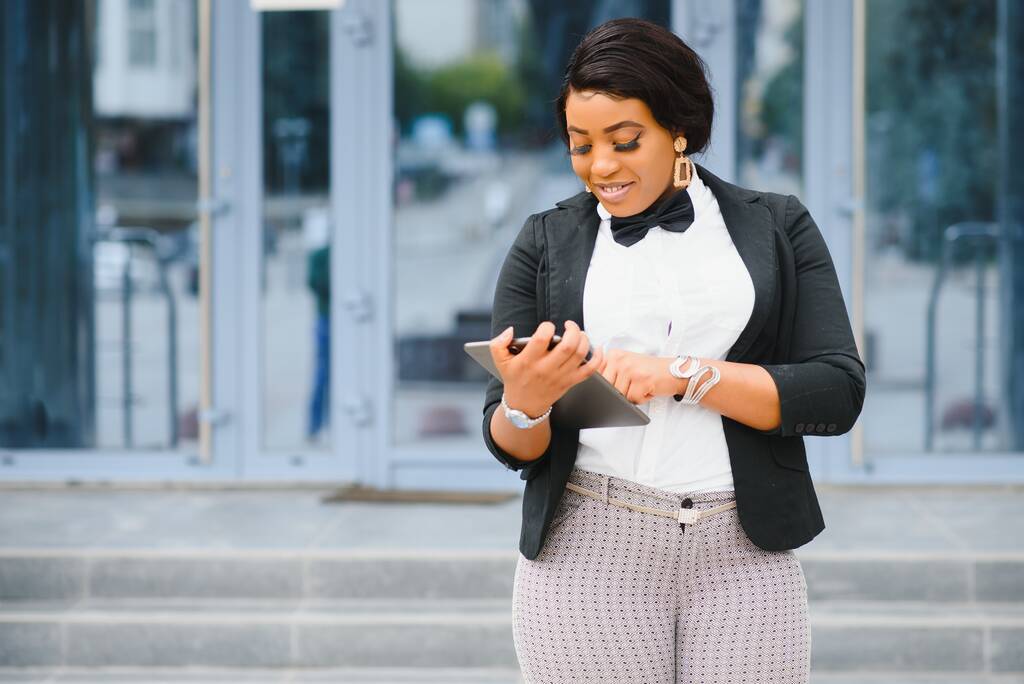 Щасливий професійний працівник біля офісного будинку. Молода афроамериканська бізнес-жінка стоїть на вулиці. Жіночий бізнес-лідер концепція - Фото, зображення