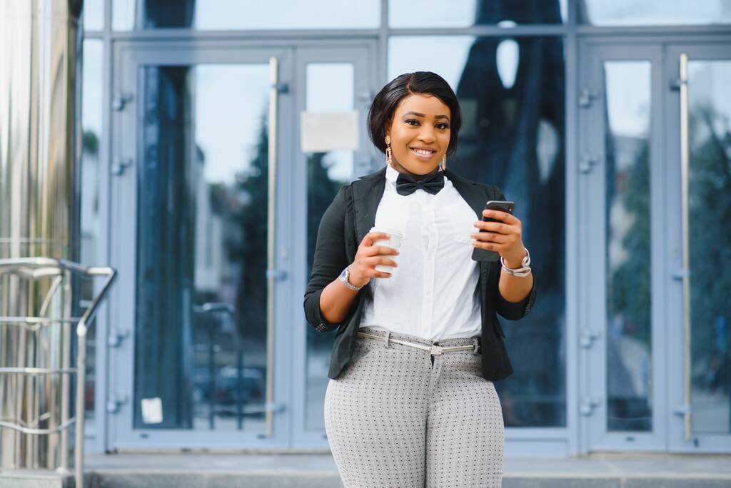 Ofis binasının yakınında başarılı bir profesyonel pozu. Genç Afrikalı Amerikalı iş kadını dışarıda duruyor. Kadın iş adamı konsepti - Fotoğraf, Görsel