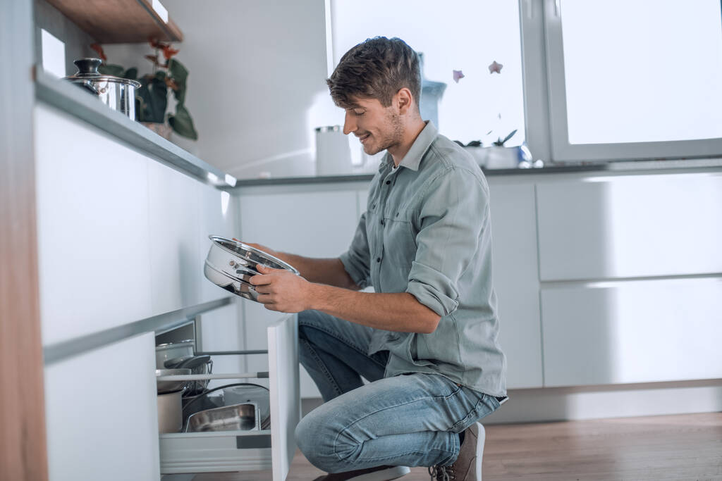 fiatal férfi néz tiszta edények mosogatógépben - Fotó, kép