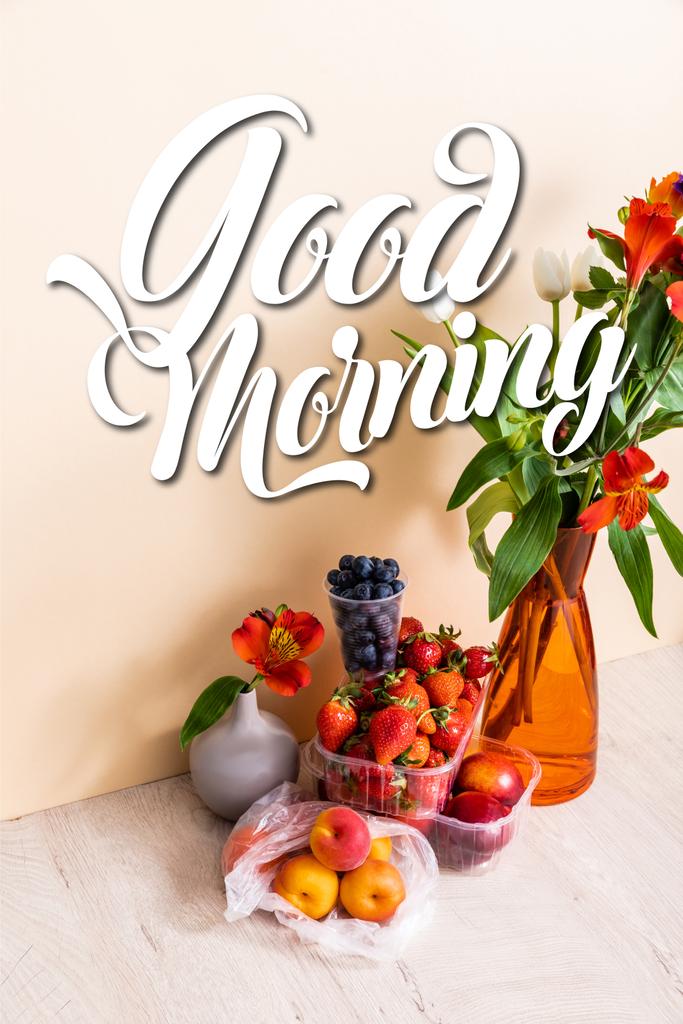 Meyvelerin yanındaki vazolarda çiçekli kompozisyon ve bej üzerine günaydın yazısı.  - Fotoğraf, Görsel