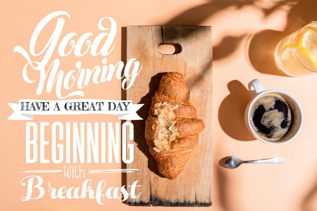 Draufsicht auf Kaffee, Wasser und Croissant auf Holzbrett auf beigem Tisch mit Guten Morgen, guten Tag, beginnend mit dem Frühstücksaufdruck - Foto, Bild