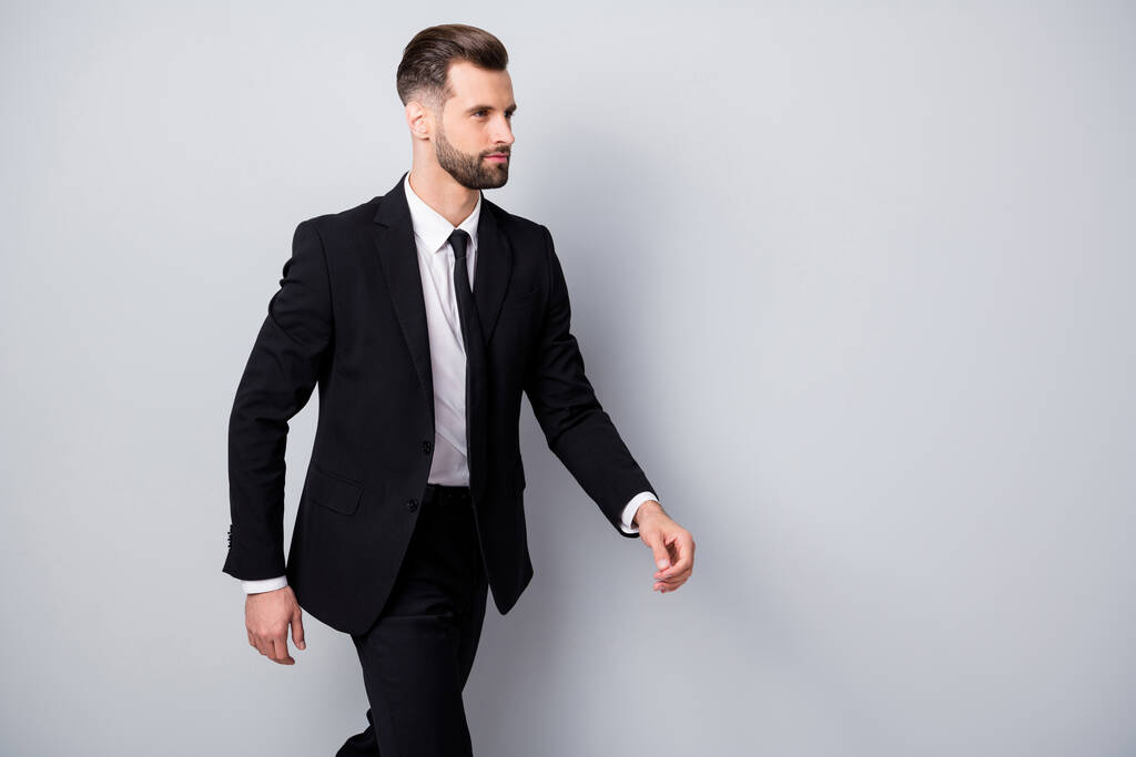 Foto del lado del perfil del trabajador carismático masculino que va a caminar sobre los socios de negocios que se reúnen usan pantalones formalwear pantalones aislados sobre fondo de color gris
 - Foto, Imagen