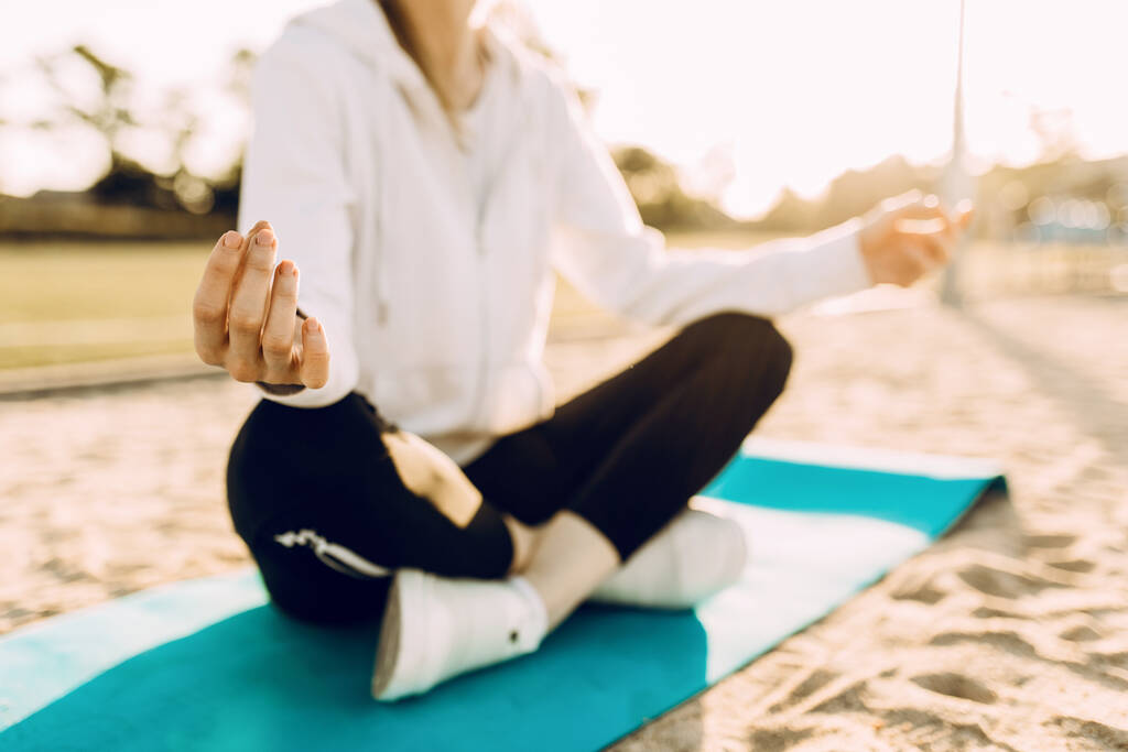 mulher esportiva pratica ioga e meditação na posição de lótus enquanto sentado em um tapete de fitness na praia pela manhã
 - Foto, Imagem