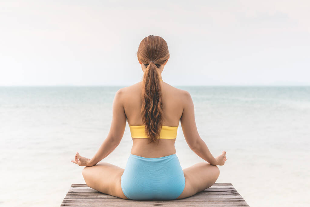 Задняя часть взглядов женщина практикует йога лотос поза для медитации летний отдых на пирсе с морским пляжем чувствуя себя таким счастливым и веселым, Путешествие в тропический пляж Таиланда, каникулы и релаксации Концепция
 - Фото, изображение