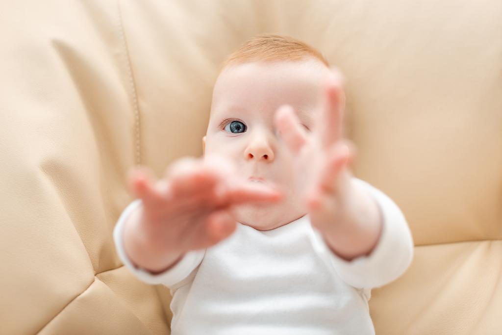 top view of cute baby boy lying with outstretched hands, selective focus - Photo, Image