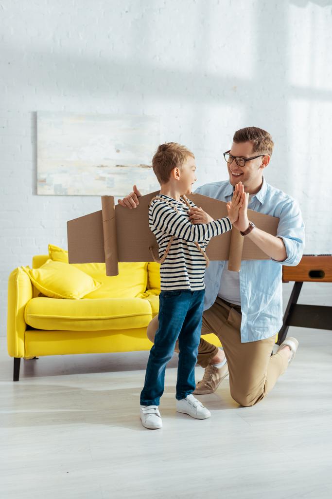 smiling father giving high five to happy son with carton wings on back - Photo, Image