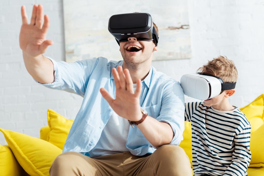 excited man gesturing with outstretched hands while using vr headsets together with son - Photo, Image