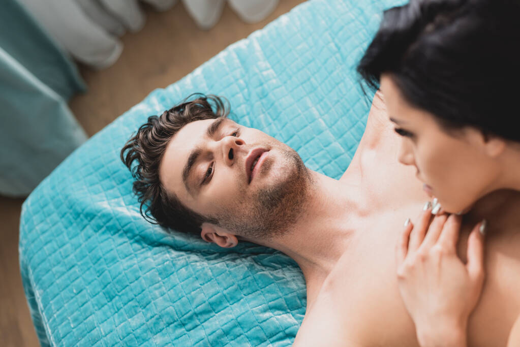 Pohled shora na muže bez trička dívajícího se na přítelkyni na posteli  - Fotografie, Obrázek
