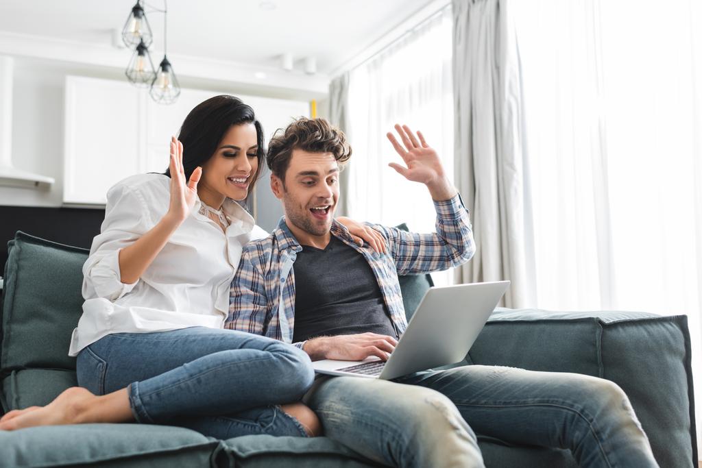 Sorrindo casal ter chamada de vídeo no laptop na sala de estar
 - Foto, Imagem