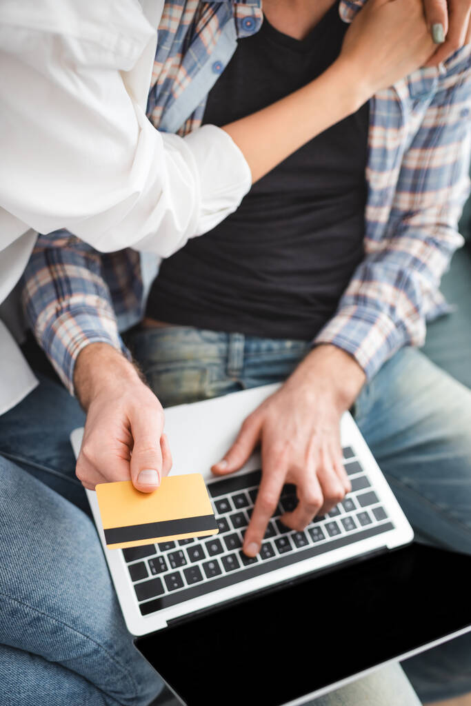 Top view of woman embracing boyfriend using credit card and laptop at home  - Photo, Image