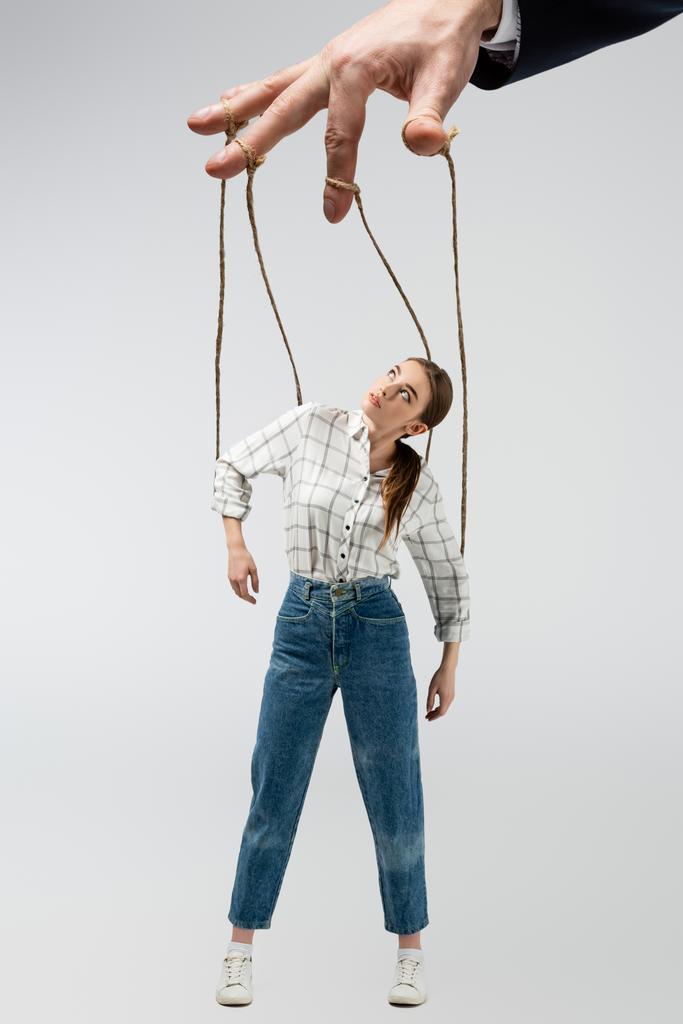 vue recadrée du marionnettiste tenant une marionnette sur des cordes isolées sur du gris - Photo, image