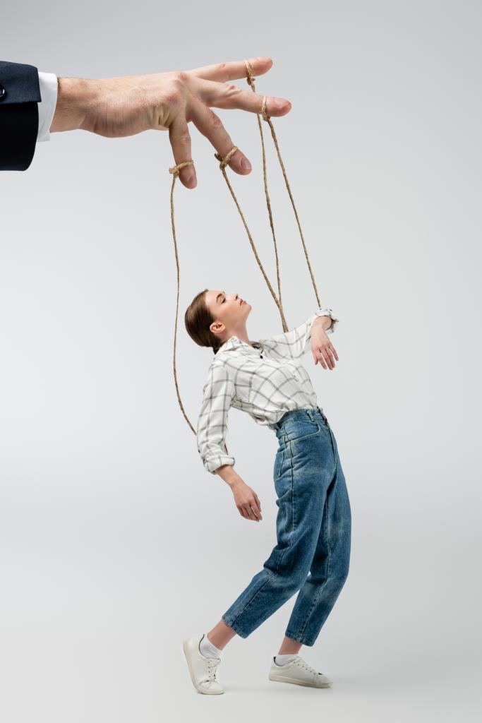 vista ritagliata di burattinaio che tiene marionetta su corde isolate su grigio - Foto, immagini