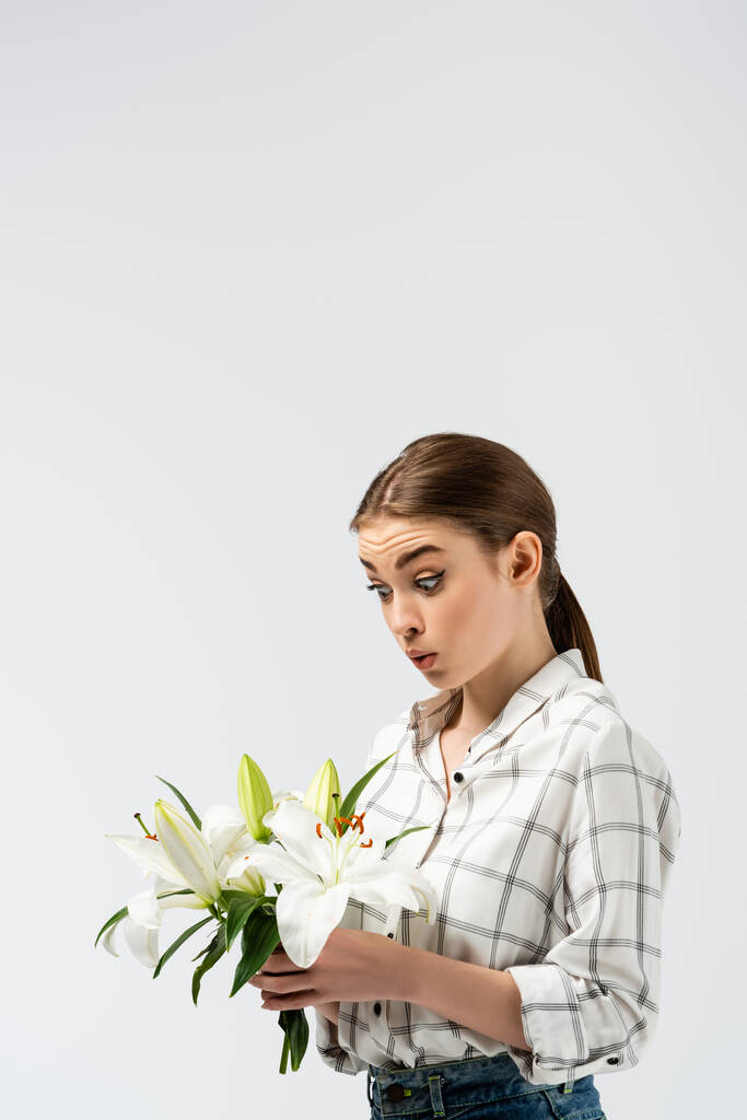 sorpresa ragazza attraente in posa come un burattino con fiori isolati su grigio - Foto, immagini