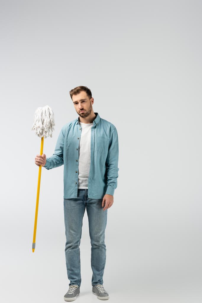 sad young man with mop isolated on grey - Photo, Image