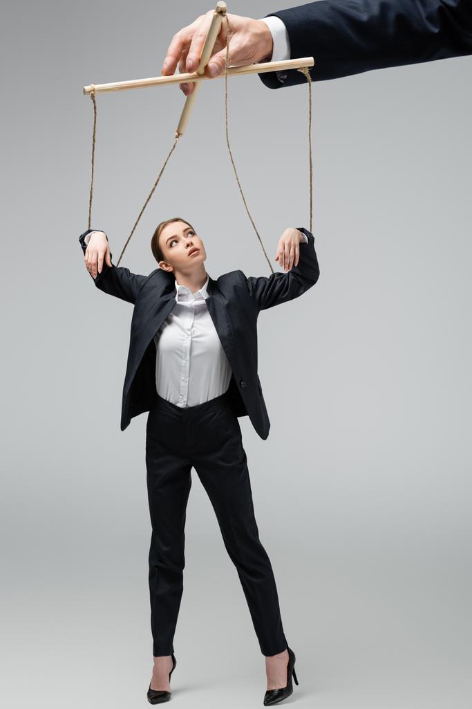 vista recortada del titiritero sosteniendo marioneta empresaria en cuerdas aisladas en gris
 - Foto, imagen