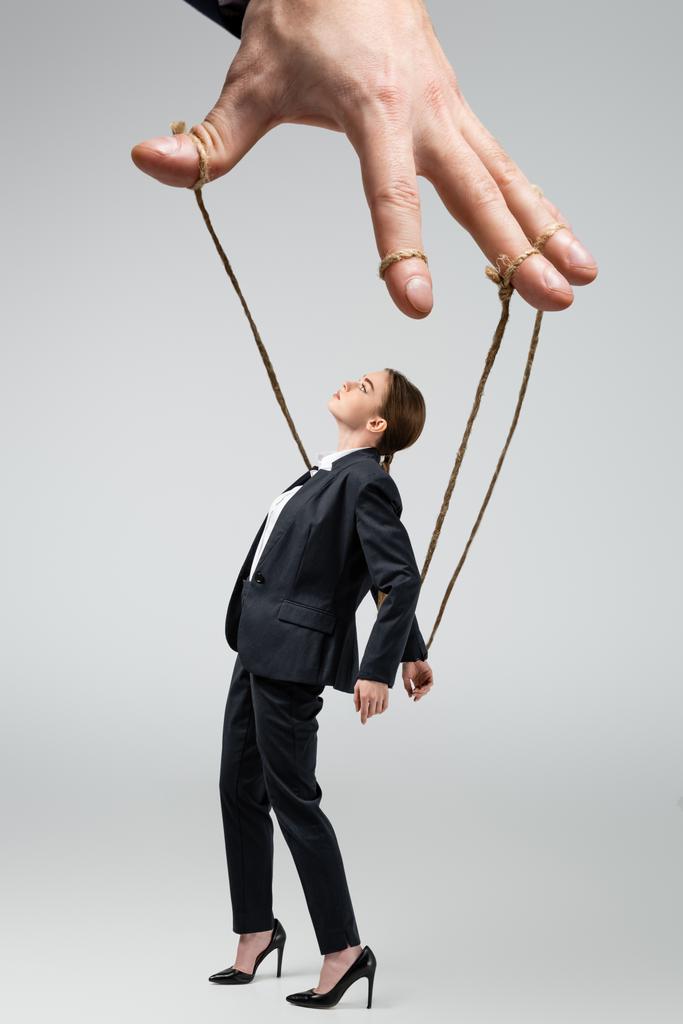 vista cortada de marionete fantoche segurando empresária em cordas isoladas em cinza
 - Foto, Imagem