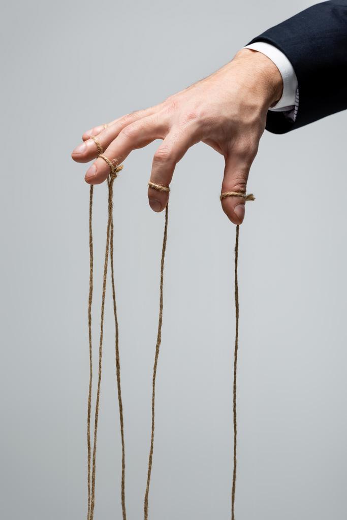 μερική άποψη του κουστουμαρισμένου μαριονετίστα με χορδές στα δάχτυλα που απομονώνονται σε γκρι - Φωτογραφία, εικόνα